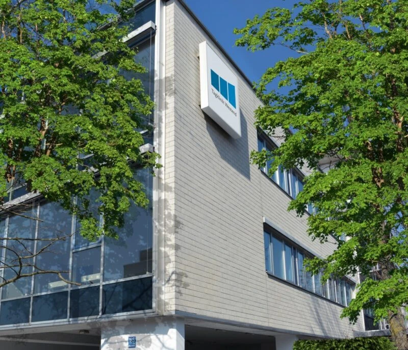 Au&szlig;enansicht des Geb&auml;udes der Psychosomatischen Tagesklinik M&uuml;nchen-Westend der Oberberg Kliniken, mit Kliniklogo an der Fassade und B&auml;umen im Vordergrund
